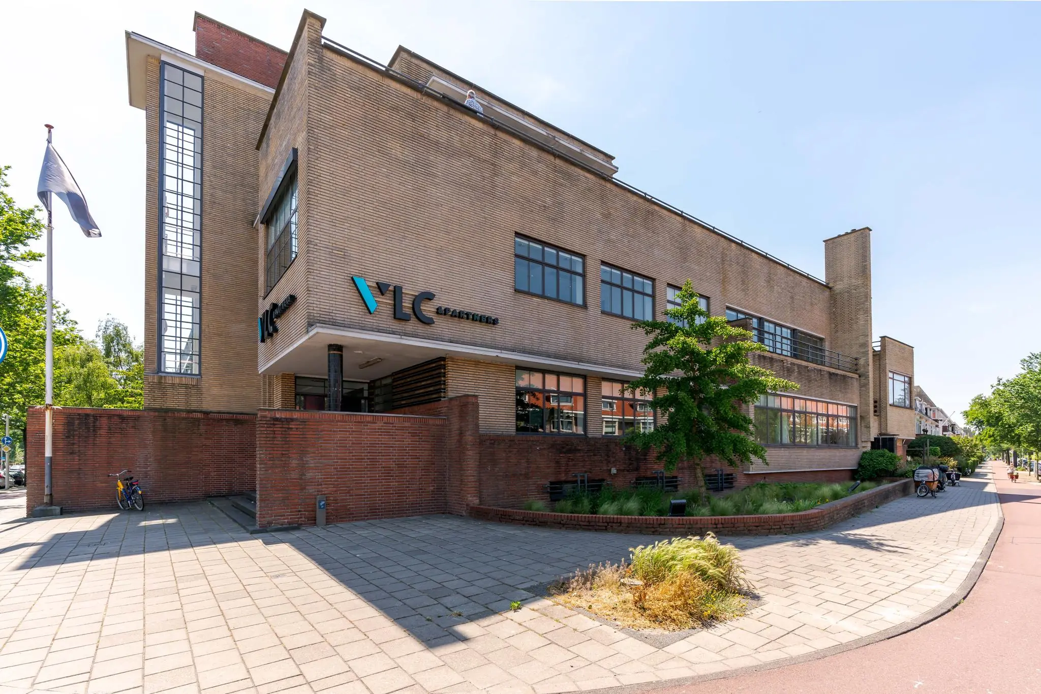 Modern kantoorpand van VLC & Partners aan de Van Alkemadelaan in Den Haag, gefotografeerd op een zonnige dag.